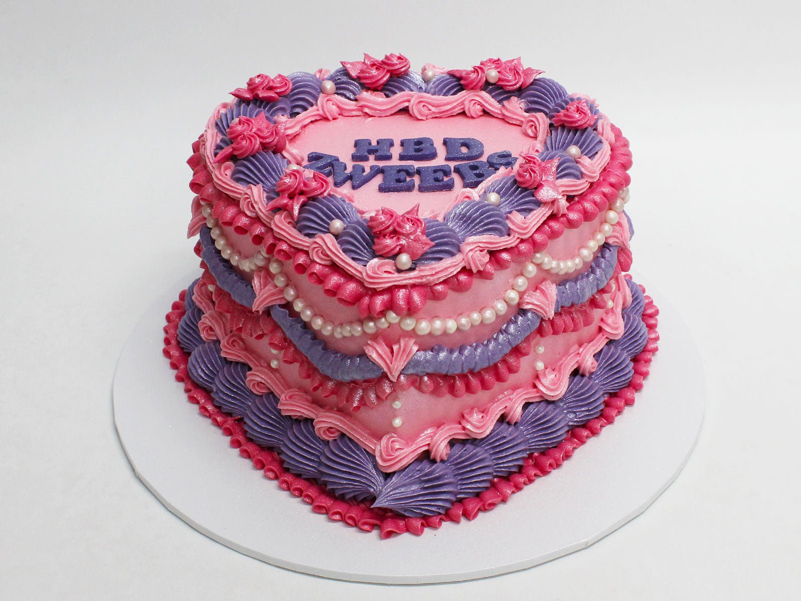 Heart-shaped Vintage Cake with pink and purple piped buttercream & Pearl Accents.